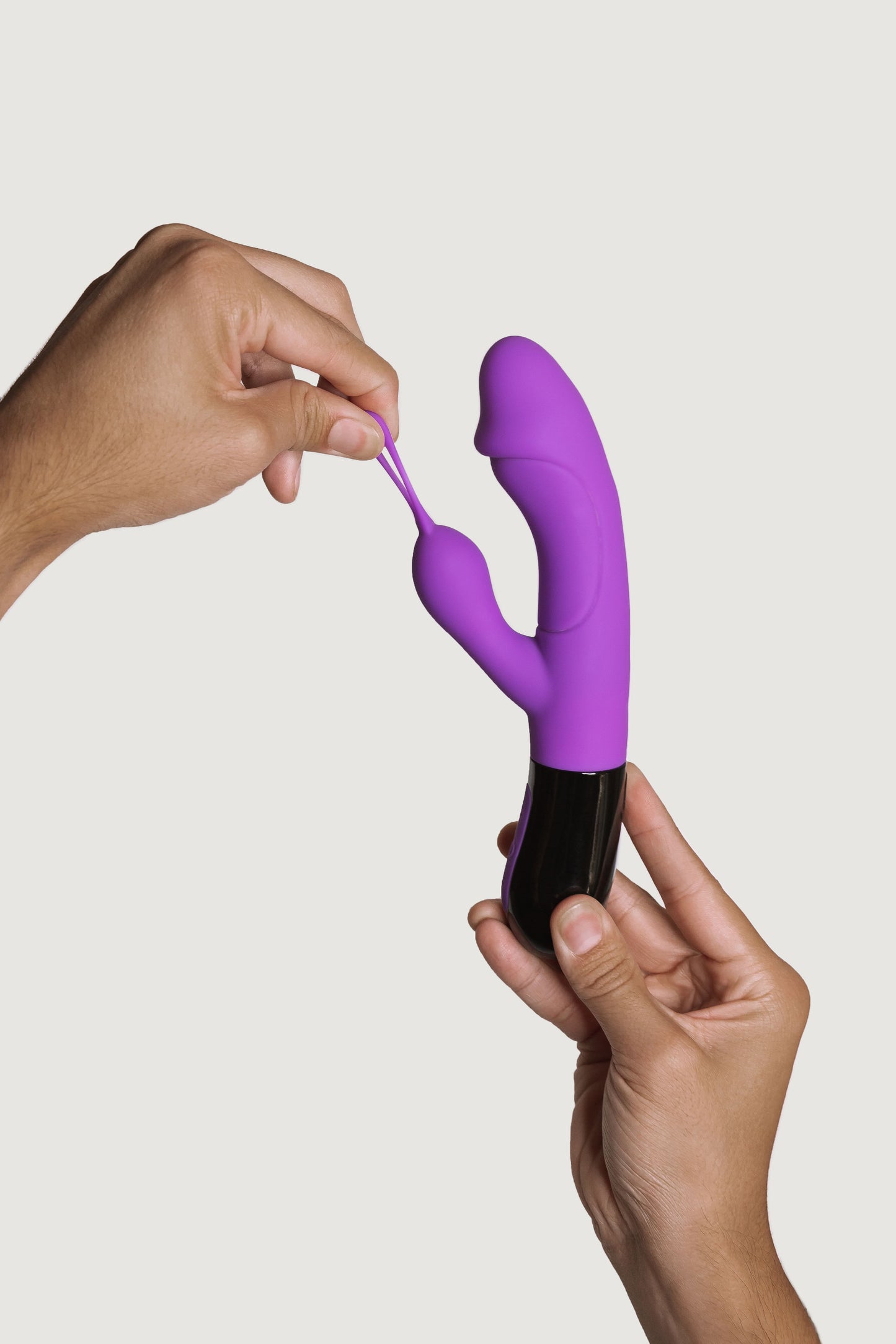 Persona tirando del lazo flexible del estimulador de clítoris del vibrador Ares 2.0, demostrando su elasticidad y diseño versátil.