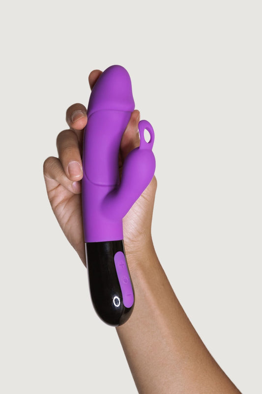 Mano sosteniendo el vibrador doble estimulación Ares 2.0 en color lila, mostrando su diseño ergonómico y suave textura de silicona.